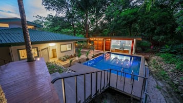 Una casa moderna con piscina, terraza y jardín.