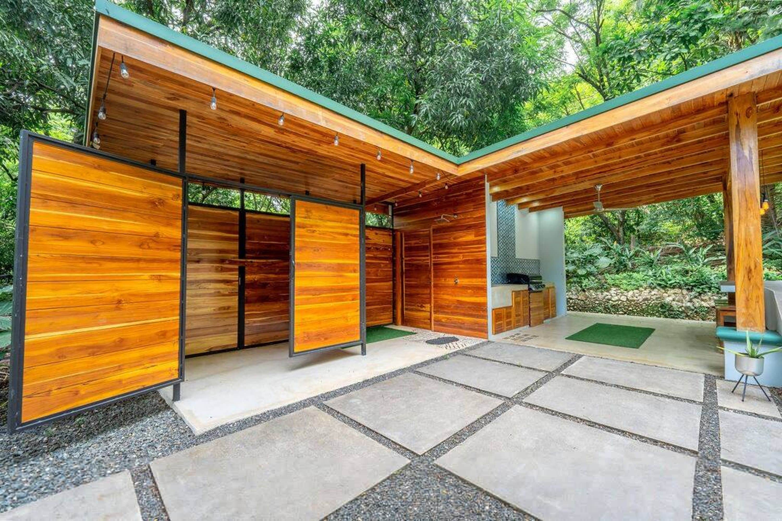 A modern wooden structure with a covered patio area, built-in seating, and a small kitchen area.