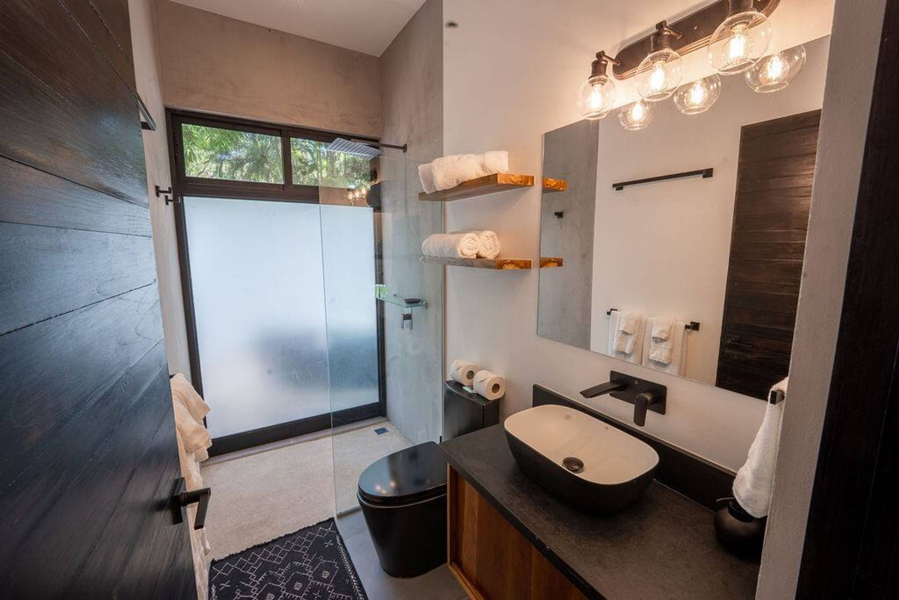 Ein modernes Badezimmer mit großem Spiegel, einem Aufsatzwaschbecken und einer Duschkabine aus Glas.