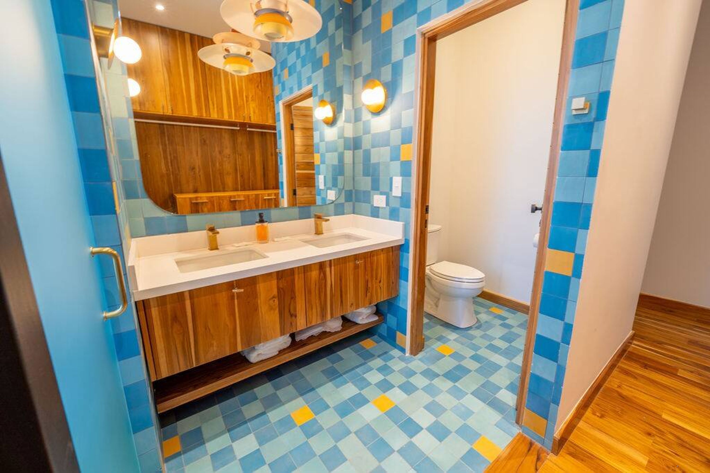 A bathroom with a wooden vanity, a white sink, and a toilet.