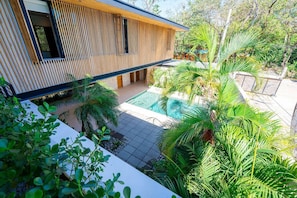 Uma casa moderna com piscina, rodeada por plantas tropicais.