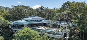 Una casa moderna con piscina, rodeada de abundante vegetación.