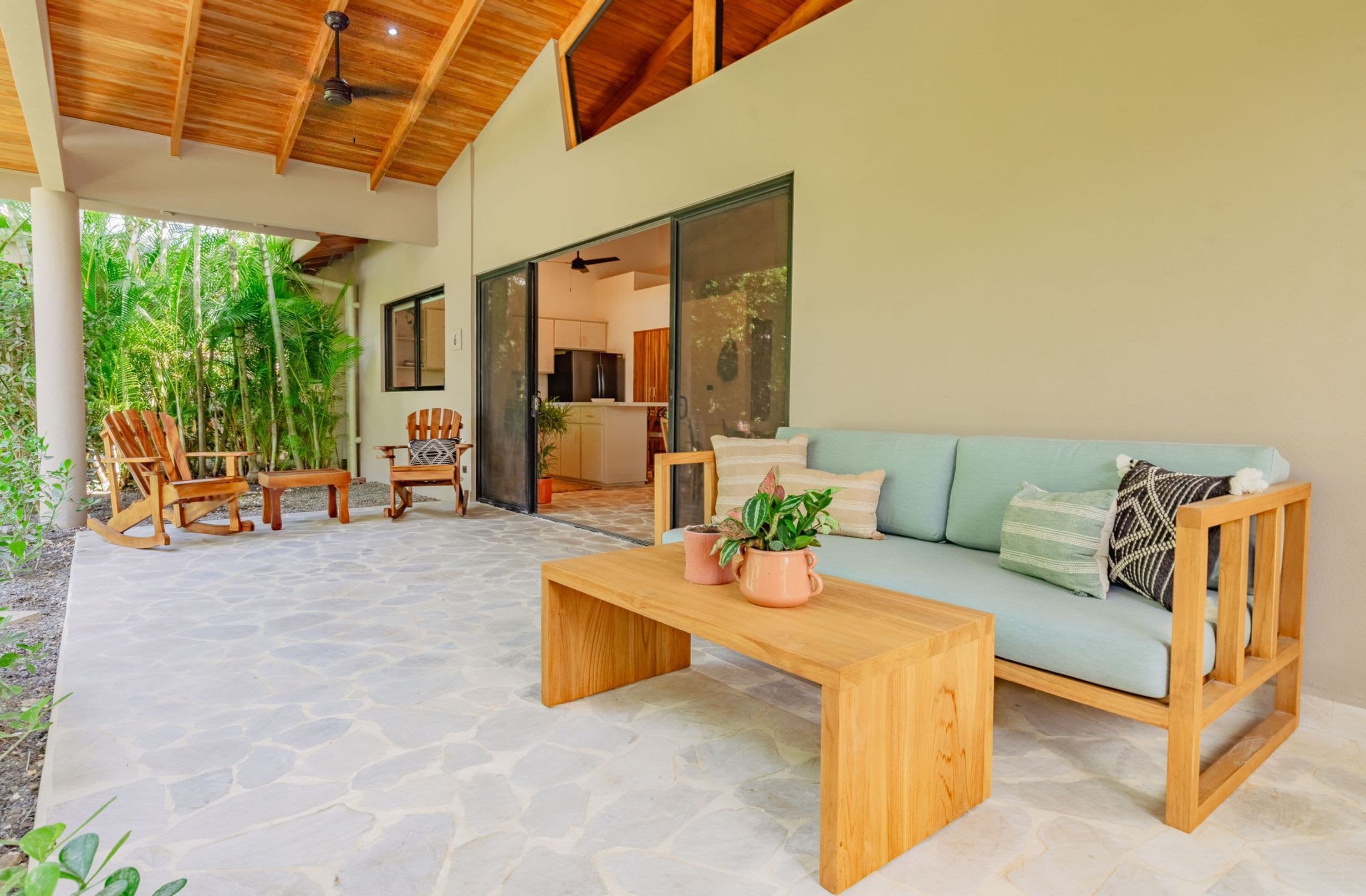 Un espacio habitable de concepto abierto con piso de piedra, muebles de madera y vista a la cocina.