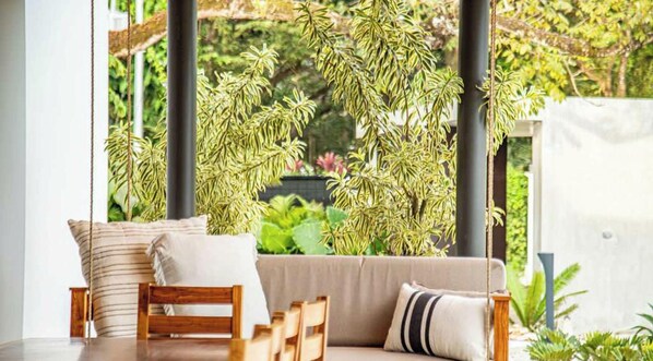 Una habitació amb un sofà, cadires i plantes penjants.