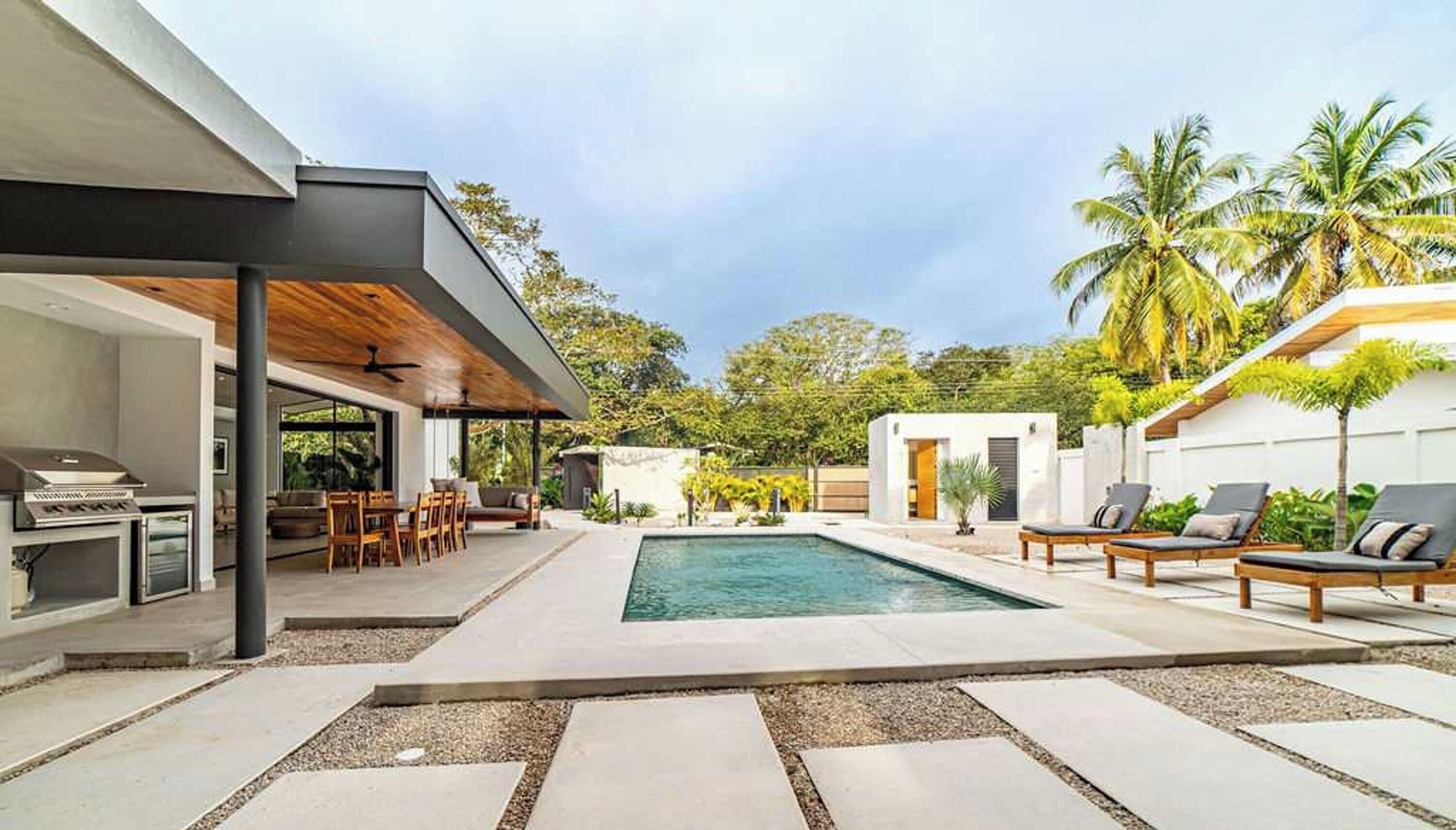 A modern outdoor pool area with a covered seating area and lounge chairs.