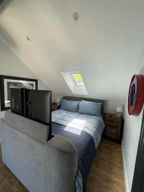 Um quarto com uma cama, uma escrivaninha, uma cadeira, uma janela e um claraboia.