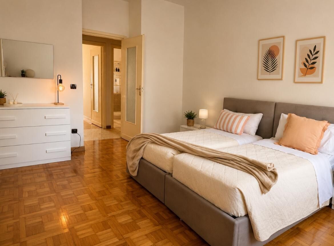 A bedroom with a bed, bedside tables, a dresser, a mirror, and framed artwork on the wall.