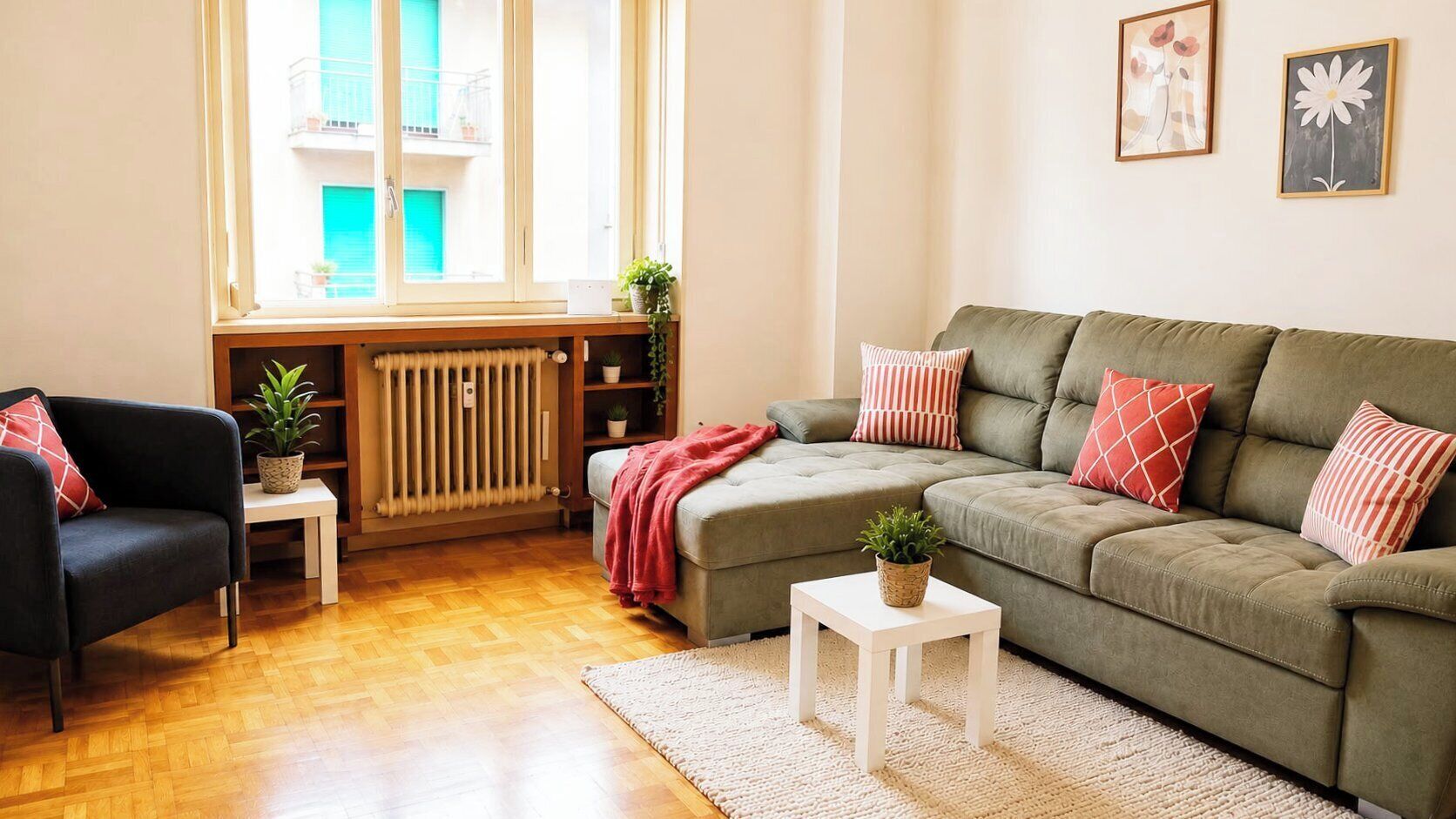 Un salon comprenant un canapé, un fauteuil, un radiateur, une fenêtre et une petite table sur laquelle est posée une plante.