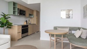 Eine moderne Küche mit Holzausbau, einer eingebauten Mikrowelle und einem Essbereich mit rundem Tisch und grünem Sofa.