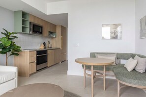 A modern kitchen with wooden cabinets, a built-in microwave, and a dining area with a round table and green sofa. - 33rd-Floor City Retreat with Balcony Views in Miami G3308 (Miami Beach)