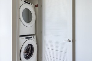 A laundry room with two stacked washing machines and a closed door. - 33rd-Floor City Retreat with Balcony Views in Miami G3308 (Miami Beach)
