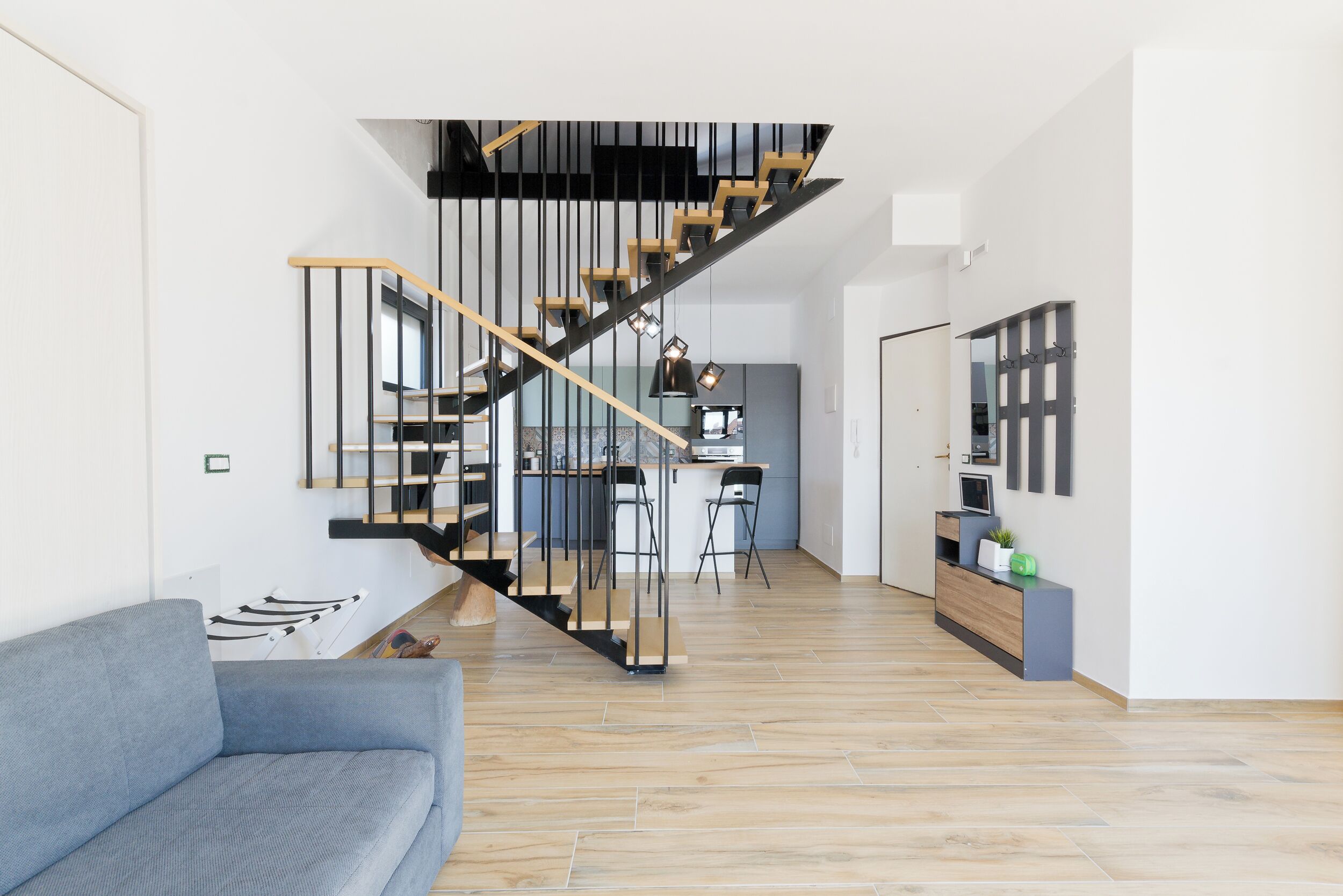 A modern interior with a staircase, a kitchen area, and a seating area.