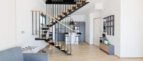 A modern interior with a staircase, a kitchen area, and a seating area.