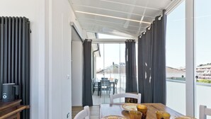 Uma sala de jantar com uma mesa posta para quatro pessoas, um radiador e vista para o exterior.