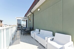 A balcony with white wicker furniture, a table, and chairs, and a view of the city. - Pescara Beach Tramonto (Pescara)