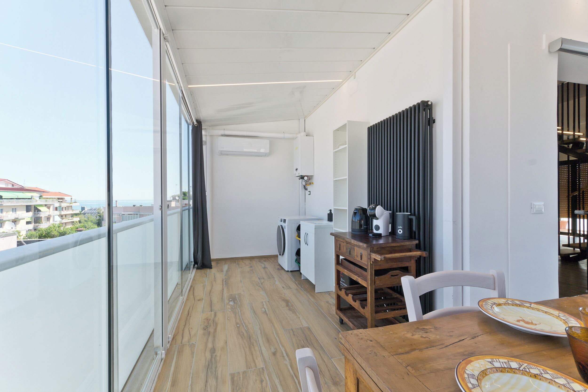 A balcony with a wooden table, chairs, and a view of buildings.