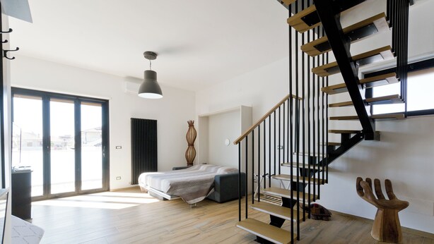Um interior moderno com escada de madeira, cama e uma janela grande.