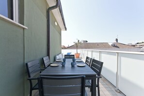 A balcony with a table set for four, chairs, and a potted plant. - Pescara Beach Tramonto (Pescara)