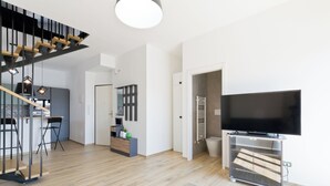 Uma sala de estar moderna com televisão de tela plana, uma escada e um espaço de jantar.