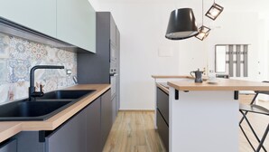 Uma cozinha moderna com uma pia preta, bancada de madeira e uma cafeteira na ilha.
