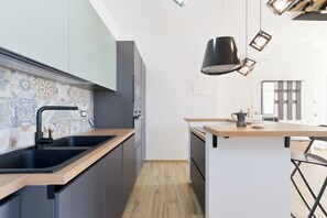 A modern kitchen with a black sink, wooden countertop, and a coffee maker on the island. - Pescara Beach Tramonto (Pescara)
