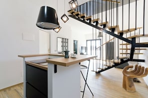 A modern kitchen with a central island, a staircase with a unique design, and a wooden hand-shaped stool. - Pescara Beach Tramonto (Pescara)