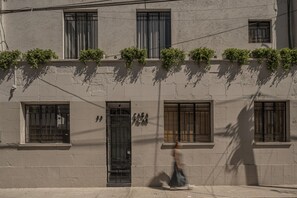 A building facade with multiple windows, some with shutters, and a door with a metal gate. - NEW Beautiful loft - KS bed- A/C (Ciudad de México)