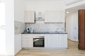 A modern kitchen with light wood cabinets, a built-in oven, and a stainless steel range hood. - Pescara Beach Alba - One Bedroom Apartment, Sleeps 4 (Pescara)