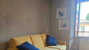 Habitación con sofá, dos almohadas, radiador y decoración en la pared.
