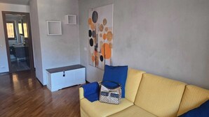 Una sala de estar con un sofá, un banco y una pared decorada con arte abstracto.