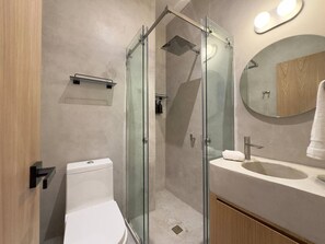 A modern bathroom with a glass-enclosed shower, a toilet, a sink, and a mirror. - Beautiful loft with private patio & A/C (Ciudad de México)
