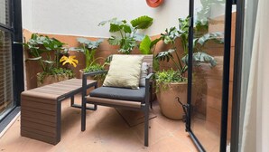 Eine kleine Terrasse mit einer gepolsterten Bank, einem Blumentopf und einem wandmontierten Blumenkasten.