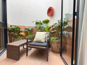 A small patio with a cushioned bench, a potted plant, and a wall-mounted planter. - Beautiful loft with private patio & A/C (Ciudad de México)