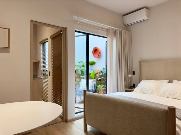 A hotel room with a bed, a round table, and a view of the outside. - Beautiful loft with private patio & A/C (Ciudad de México)
