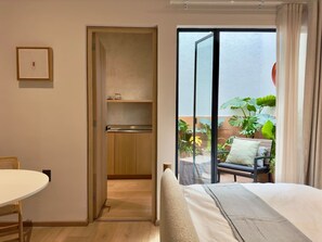A hotel room with a bed, a dining table, a kitchenette, and a balcony with plants. - Beautiful loft with private patio & A/C (Ciudad de México)