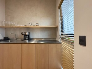 A modern kitchen with a built-in coffee maker, a wooden countertop, and a window with blinds. - Beautiful loft with private patio & A/C (Ciudad de México)