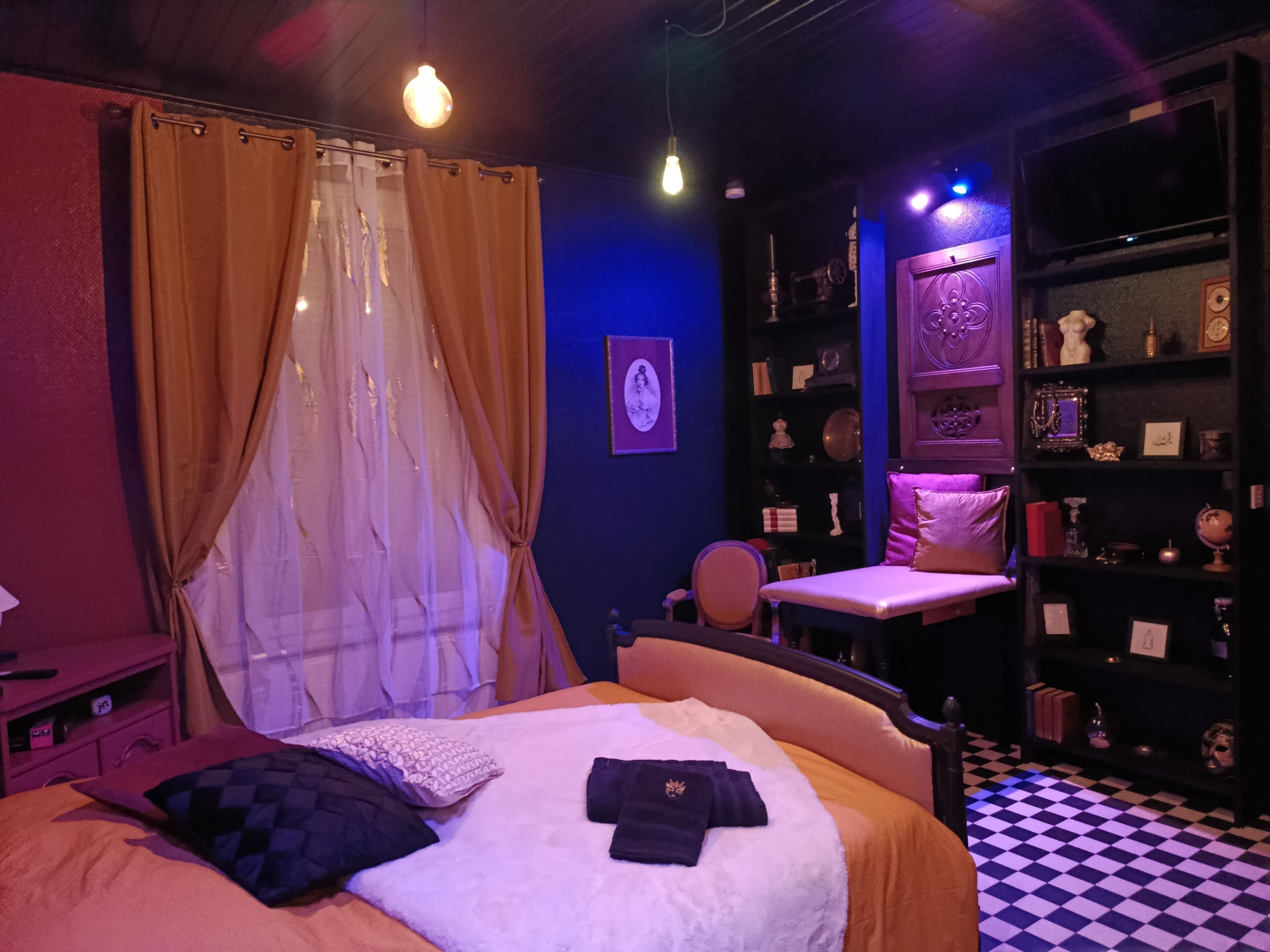 Een kamer met een bed, een stoel, een bureau en een boekenplank.