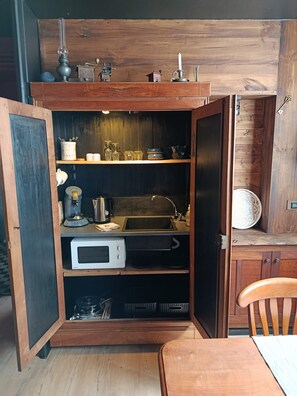A compact kitchen with a built-in microwave, a sink, and a wooden cabinet above.