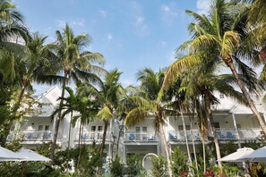 Ein weißes, mehrstöckiges Hotel mit Balkonen, umgeben von Palmen und tropischer Vegetation.