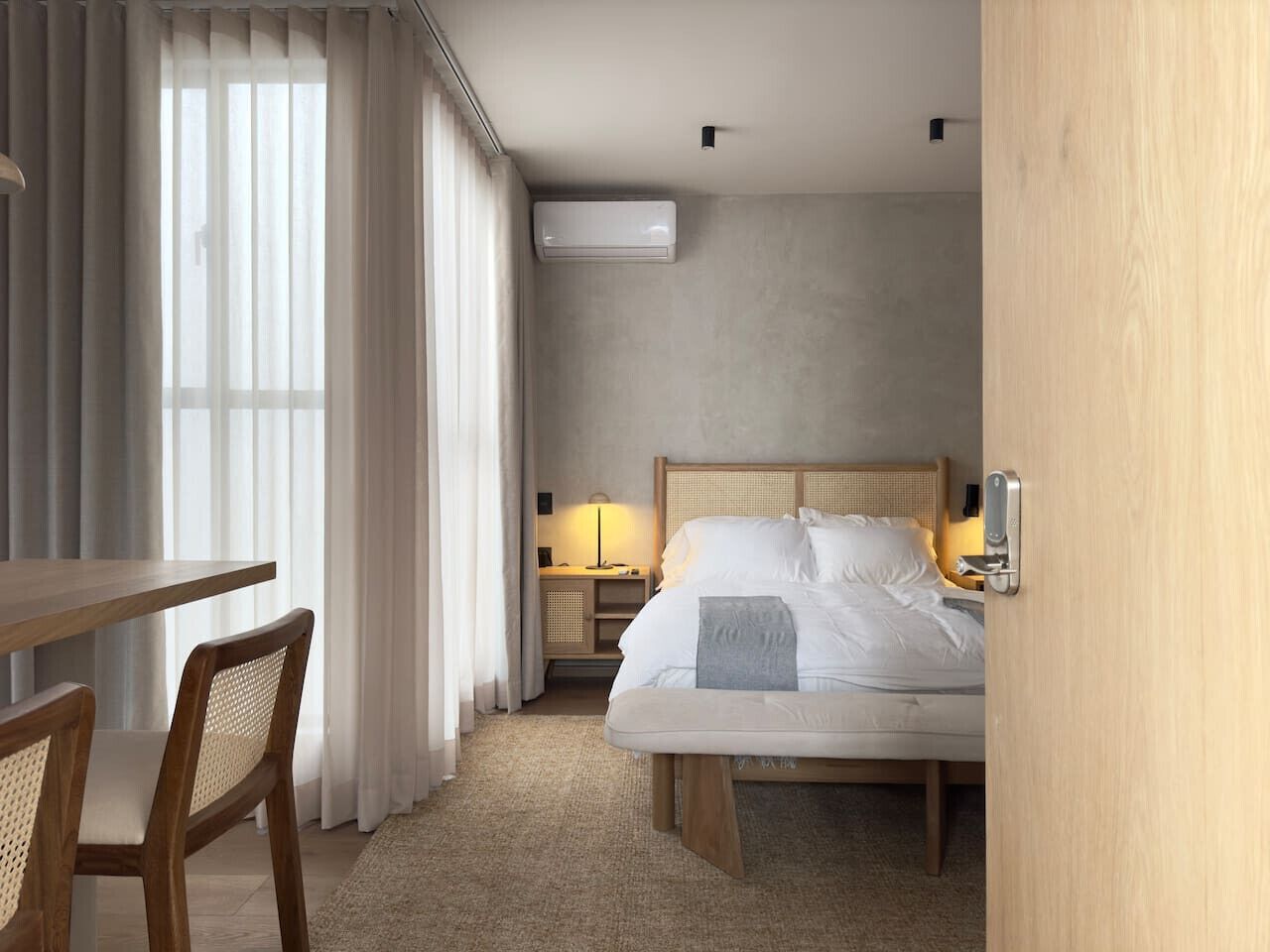 Une chambre d’hôtel avec un lit, une table de chevet, une lampe et une fenêtre avec des rideaux.