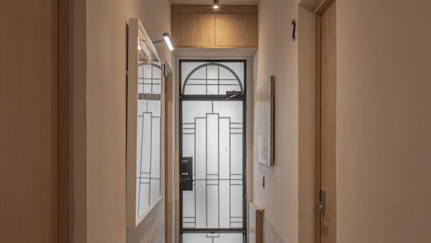 Un pasillo con una puerta al final, un accesorio de iluminación en el techo y un cuadro en la pared.