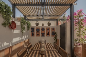 Eine Terrasse im Freien mit Holztisch, Stühlen, Topfpflanzen und dekorativen Vasen.
