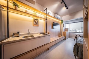 Una cocina moderna con horno integrado, un lavamanos y una ventana con vistas a un paisaje urbano.