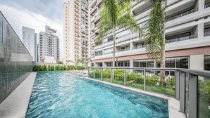 Ein Pool mit Glasbarriere, umgeben von Hochhäusern und Palmen.