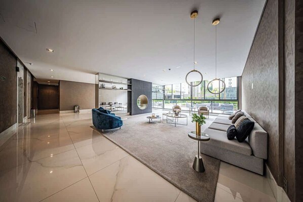 Un amplio salón con sofá, mesa de centro y una silla azul.