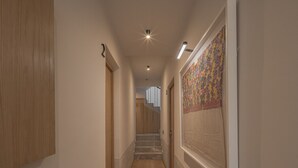 Un passadís amb terres de fusta, un penjall de paret amb dibuixos i una escala al fons.
