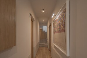 Ein Flur mit Holzboden, einem Wandbehang mit Muster und einer Treppe im Hintergrund.
