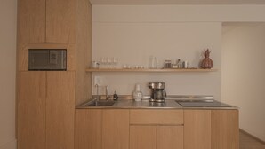 Una cuina moderna amb armaris de fusta, microones integrat, cafetera i portaflors per a vins.