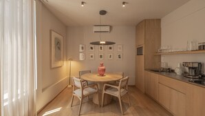 Una cuina moderna amb armaris de fusta, una taula de dinar amb caires i una làmpada penjant.