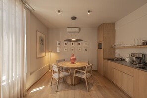 Eine moderne Küche mit Holzausstattung, einem Esstisch mit Stühlen und einer Pendelleuchte.